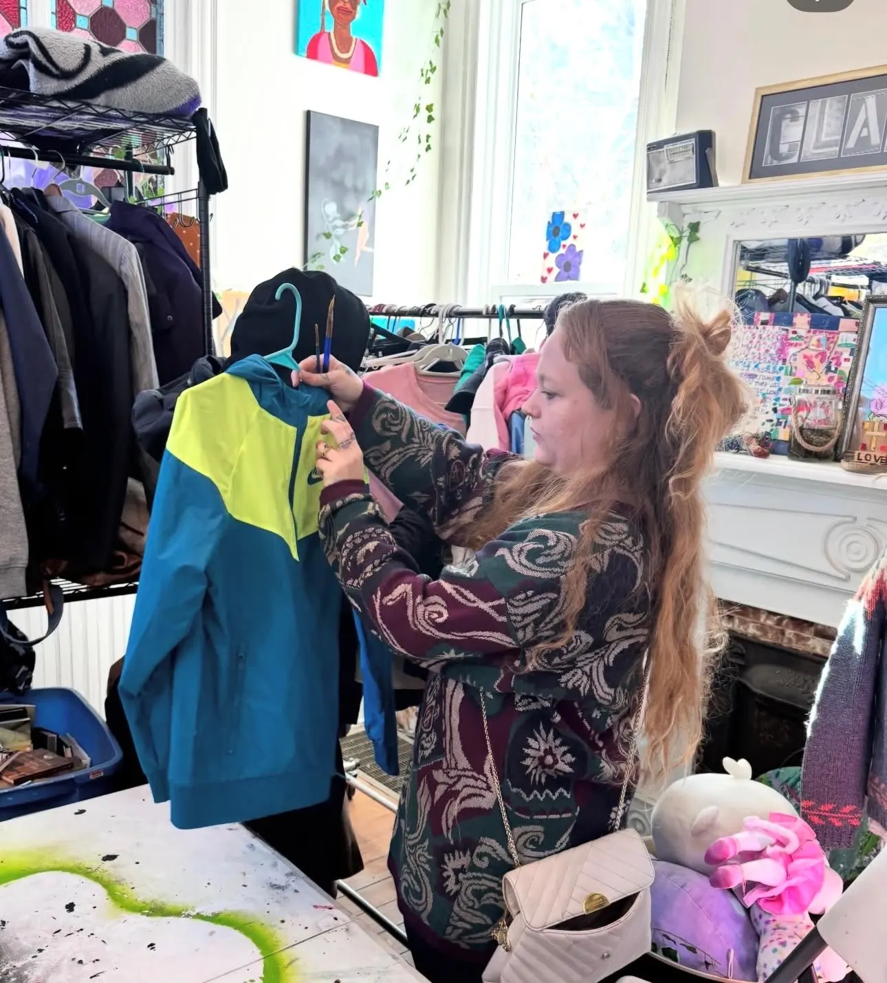 A visitor holds up a blue and yellow jacket from the racks at Bella's Free Community Store