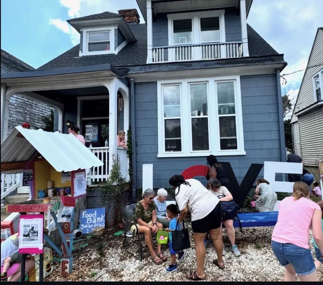 Neighbors gather around the big LOVE letters in front of The Clarity House on a community day