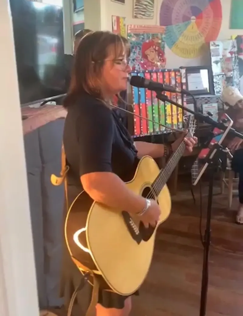 A performer with an acoustic guitar plays to a full front room